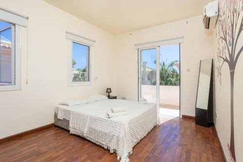 een witte slaapkamer met een groot bed en ramen bij Villa Miracle in Paralimni