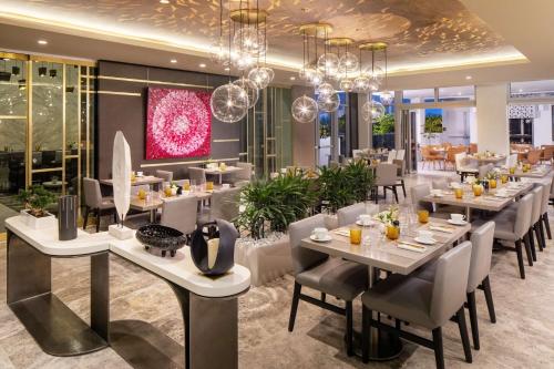 a restaurant with white tables and chairs and chandeliers at Hilton Miami Aventura in Aventura