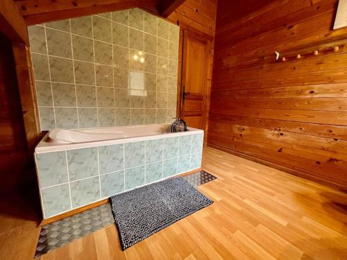 ein Badezimmer mit einer Badewanne und einer Holzwand in der Unterkunft Chalet Baudelaire, 4* beau et authentique in Xonrupt-Longemer