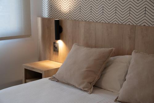 a bed with two pillows and a wooden head board at Urbana Class Hotel in Mendoza