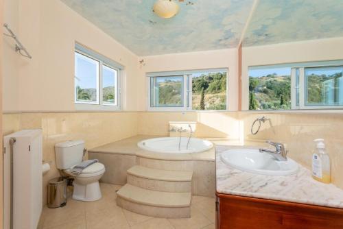 a bathroom with a tub and a toilet and a sink at Villa Asimenia in Agia Triada