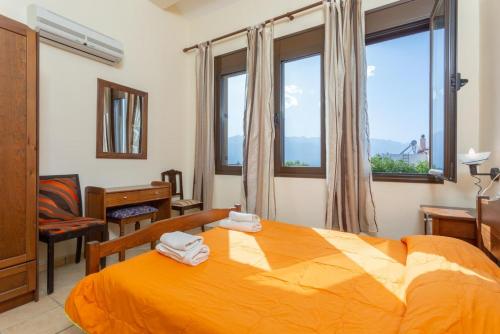 a bedroom with a bed and a desk and windows at Villa Kefalas in Epáno Kefalás