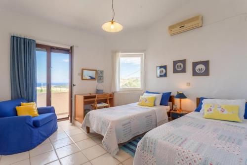 a bedroom with two beds and a blue chair at Villa Armi in Episkopí- Rethimno