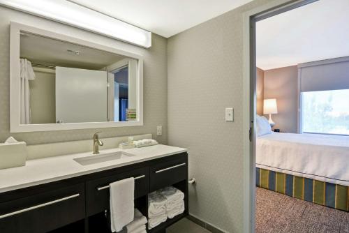 een badkamer met een wastafel, een bed en een spiegel bij Home2 Suites by Hilton Miramar Ft. Lauderdale in Miramar