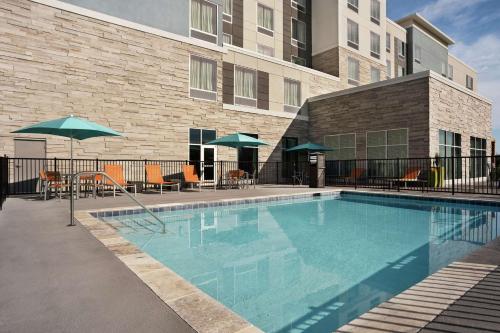 a swimming pool with chairs and umbrellas next to a building at Homewood Suites By Hilton Florence in Florence