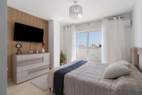 1 dormitorio con 1 cama y TV en la pared en Townhouse with 3 bedrooms and sea views from the roof terrace, en Torremolinos