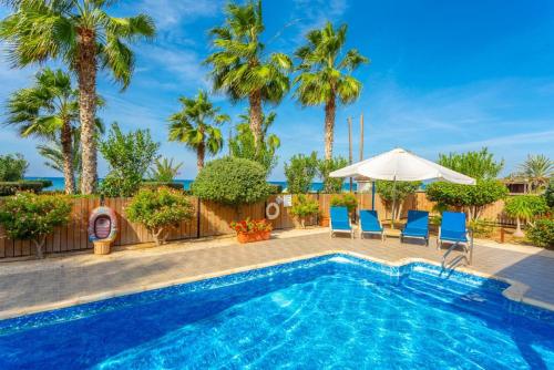 a pool with chairs and an umbrella and palm trees at Villa Jan Lui in Argaka