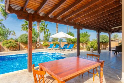 a patio with a wooden table and chairs and a pool at Villa Jan Lui in Argaka