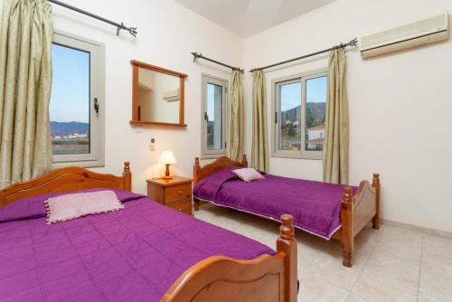 Duas camas num quarto com janelas e lençóis roxos em Villa Jan Lui em Argaka