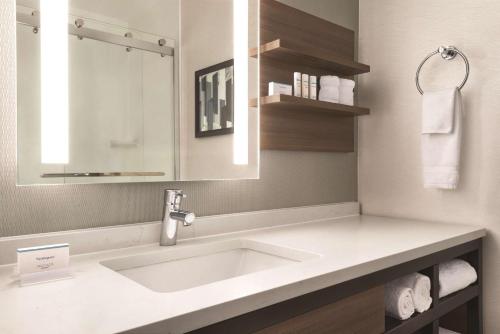 a bathroom with a sink and a mirror and towels at Hilton Garden Inn Fort Wayne in Fort Wayne