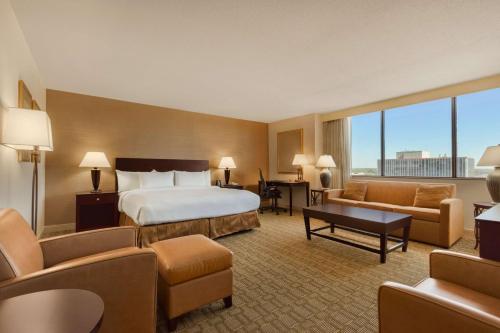 a hotel room with a bed and a couch and chairs at Hilton Fort Wayne at the Grand Wayne Convention Center in Fort Wayne