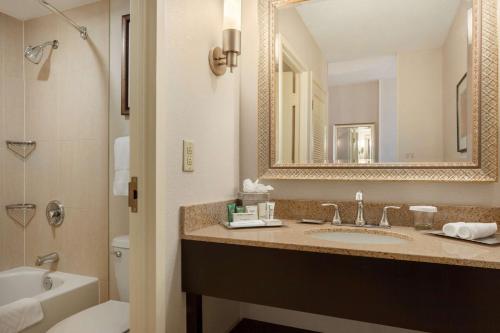 a bathroom with a sink and a toilet and a mirror at Hilton Fort Wayne at the Grand Wayne Convention Center in Fort Wayne