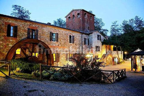 an old brick building with a tower on top of it at La Fattoria Montalcinello in Chiusdino