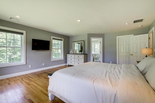 a bedroom with a large white bed and two windows at Coastal Retreat at Mystic Seaport Heights in Mystic