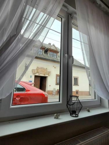 a window with a red car parked in a garage at Noclegi Przy Niemczówce in Chęciny