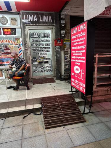 a man sitting in a chair in front of a store at Hotel lima lima in Pattaya