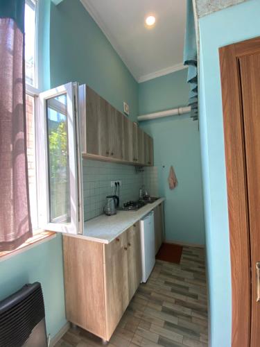 a kitchen with wooden cabinets and a window at Eli’s home in Borjomi