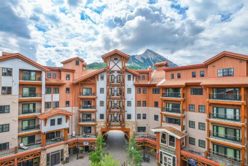 um edifício de apartamentos com uma montanha ao fundo em The Lodge at Mountaineer Square em Mount Crested Butte