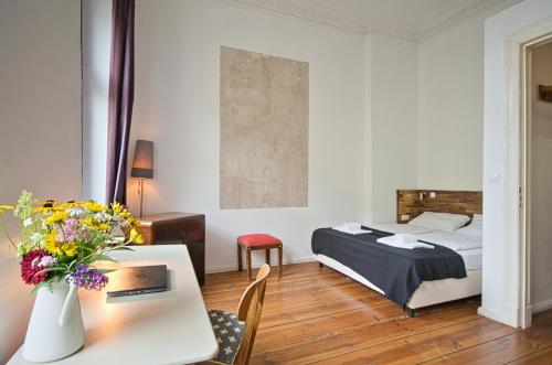 ein Schlafzimmer mit einem Bett und einem Tisch mit einer Blumenvase in der Unterkunft 2 Bedroom Apartment (ABEMI) in Berlin