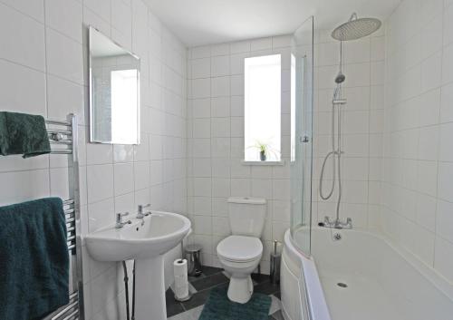 a white bathroom with a toilet and a sink at The Crow's Nest in Broadstairs
