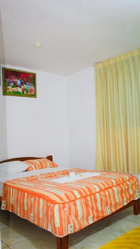 um quarto com uma cama com um edredão laranja e uma janela em Hospedaje chanari em La Merced