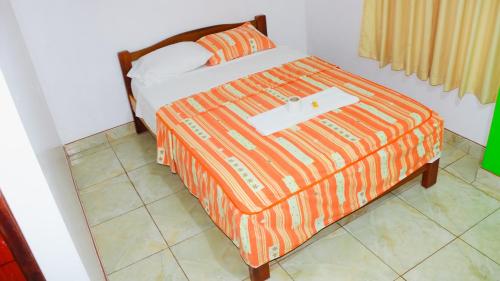 a bed with an orange comforter with a white object on it at Hospedaje chanari in La Merced