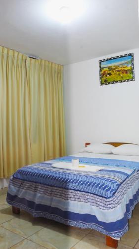 a bedroom with a bed with a blue blanket on it at Hospedaje chanari in La Merced