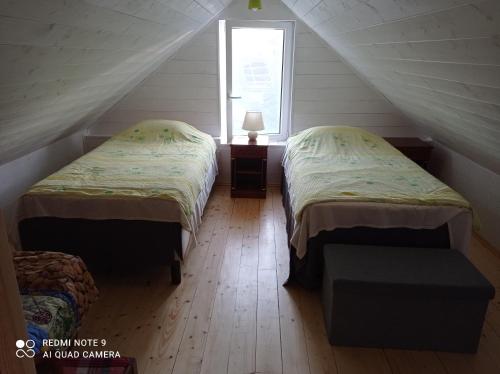 two beds in a attic room with a window at RYTO GARSAI in Merkinė