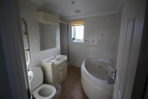 a bathroom with a sink and a tub and a toilet and a bath tub at Atlantic Reach Cottages, Newquay 6 miles, 2 Bedrooms in Newquay