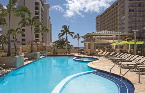 uma grande piscina com cadeiras e um hotel em Embassy Suites by Hilton Waikiki Beach Walk em Honolulu