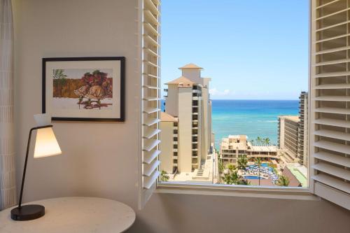 a room with a window with a view of the ocean at Embassy Suites by Hilton Waikiki Beach Walk in Honolulu