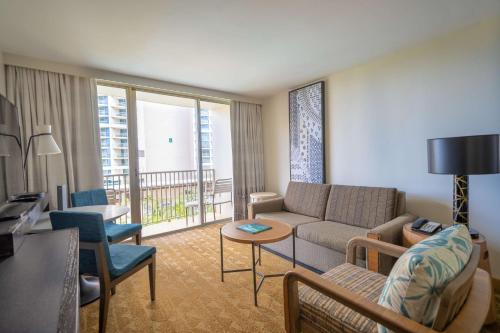 a living room with a couch and a table and chairs at Embassy Suites by Hilton Waikiki Beach Walk in Honolulu