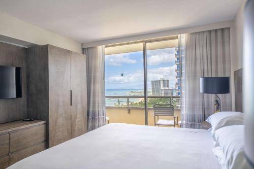 a bedroom with a large bed and a large window at Embassy Suites by Hilton Waikiki Beach Walk in Honolulu