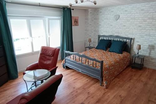 een slaapkamer met een bed, een bank en een stoel bij Duplex Camélia T3 avec jardin in Clohars-Carnoët