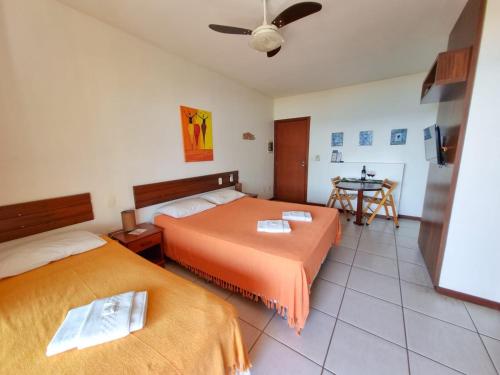 a hotel room with two beds and a table at Apart Hotel Beira do Mar in Florianópolis