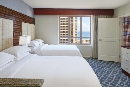 Hilton Grand Vacations Club Grand Waikikian Honolulu في هونولولو: غرفه فندقيه ثلاث اسره ونافذه