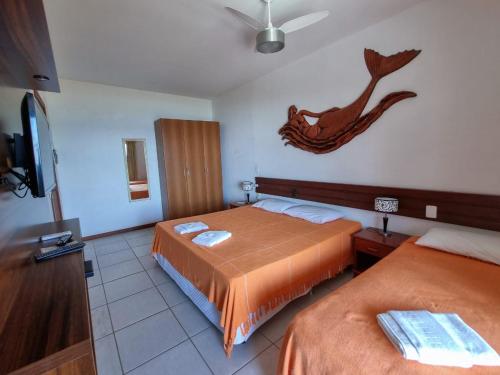 a hotel room with two beds and a tv at Apart Hotel Beira do Mar in Florianópolis