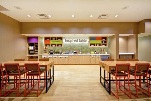 a large kitchen with wooden tables and red chairs at Home2 Suites At The Galleria in Houston