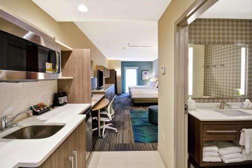 uma cozinha com um lavatório e um quarto com uma cama em Home2 Suites At The Galleria em Houston