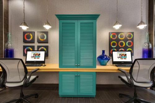 a desk with a green door and two laptops at Home2 Suites by Hilton Houston Stafford - Sugar Land in Stafford