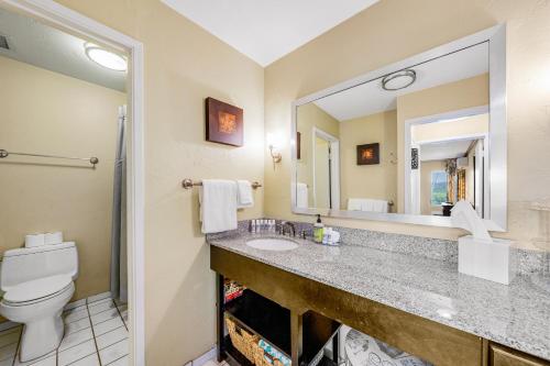 a bathroom with a sink and a toilet and a mirror at Plantation Hale J11 in Kapaa