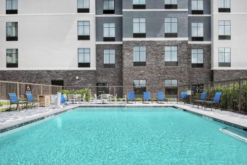 a swimming pool with blue chairs and a building at Homewood Suites By Hilton Houston Memorial in Houston