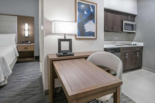 ein Hotelzimmer mit einem Schreibtisch und einem Bett sowie einer Küche in der Unterkunft Homewood Suites By Hilton Houston Memorial in Houston
