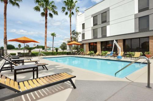 a pool at a hotel with benches and umbrellas at Hampton Inn - Houston/Brookhollow in Houston