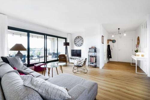 a living room with a couch and a clock on the wall at Superbe appartement de 120m2 et 2 balcons, à 10min à pieds de la plage - 3 chambres - parking privé in Le Pouliguen