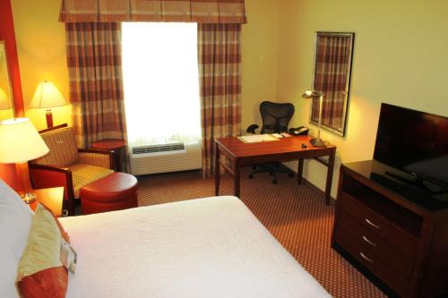 a hotel room with a bed and a desk and a television at Hilton Garden Inn Houston West Katy in Katy