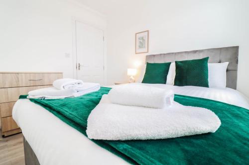 sypialnia z dużym białym łóżkiem z zielonymi akcentami w obiekcie NEW BUILD house with GATED DRIVEWAY! FREE wifi! w Luton