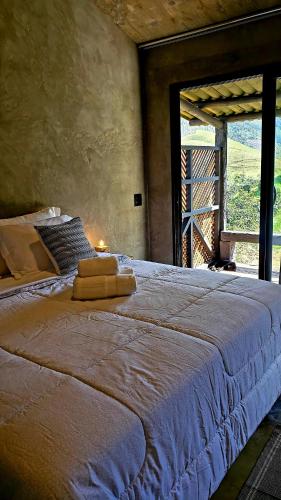 a bedroom with a large bed with a large window at Hospedagem Bangalô Patrimônio da Penha in Divino de São Lourenço