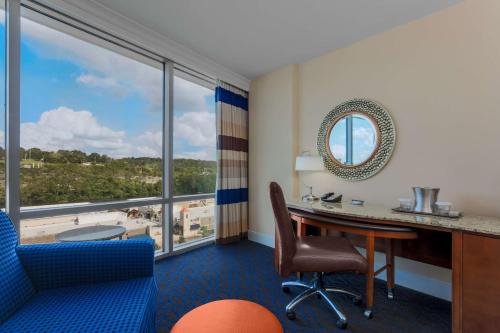 Habitación con escritorio, silla y ventana grande. en Hilton Branson Convention Center, en Branson