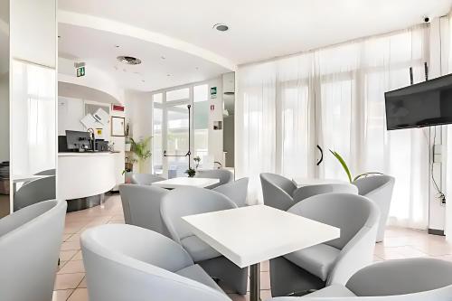 - une salle d'attente avec des tables et des chaises blanches dans l'établissement Hotel Villa Argia Rimini Marina Centro, à Rimini